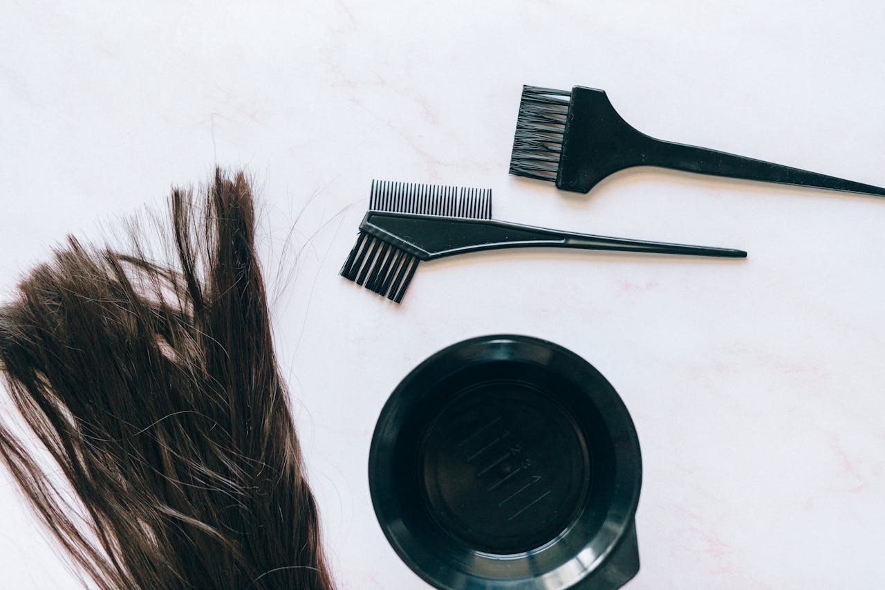 Top view of hair coloring tools and hair strands on a white background.